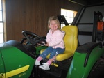 "Wow, this John Deere is a lot bigger than dad's!"  Paige poses on the tractor in the barn.